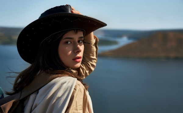 Attractive woman in cowboy hat standing on high hill